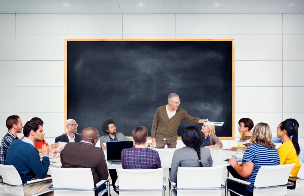 A man stood in front of a blackboard, teaching a class.